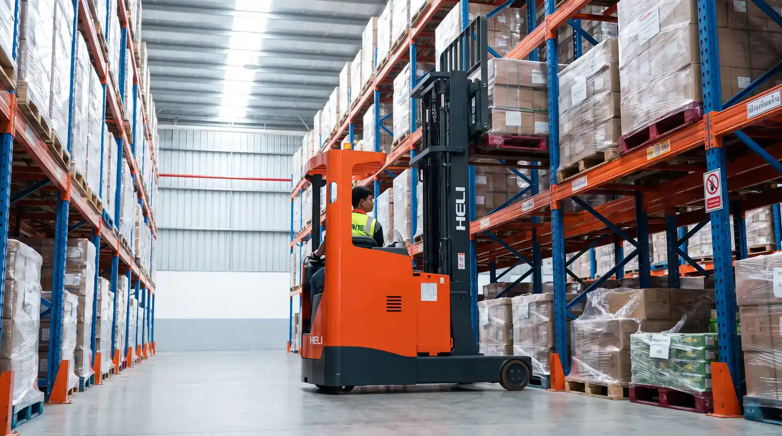 รถโฟล์คลิฟท์ไฟฟ้ายืนขับ Reach Truck ในช่องทางแคบระหว่างชั้นวาง